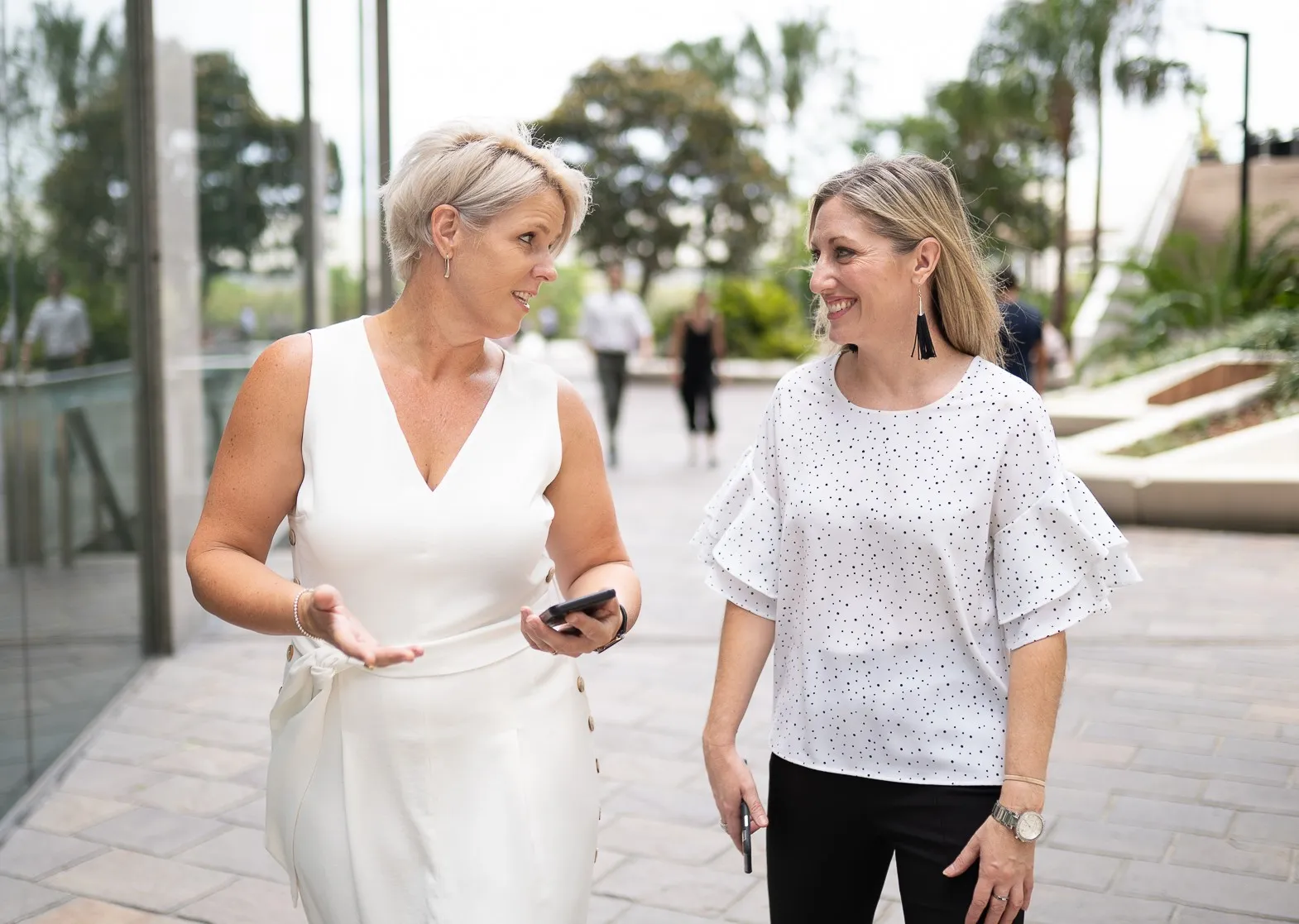 Kristy walking and talking with a business leader outside an office building